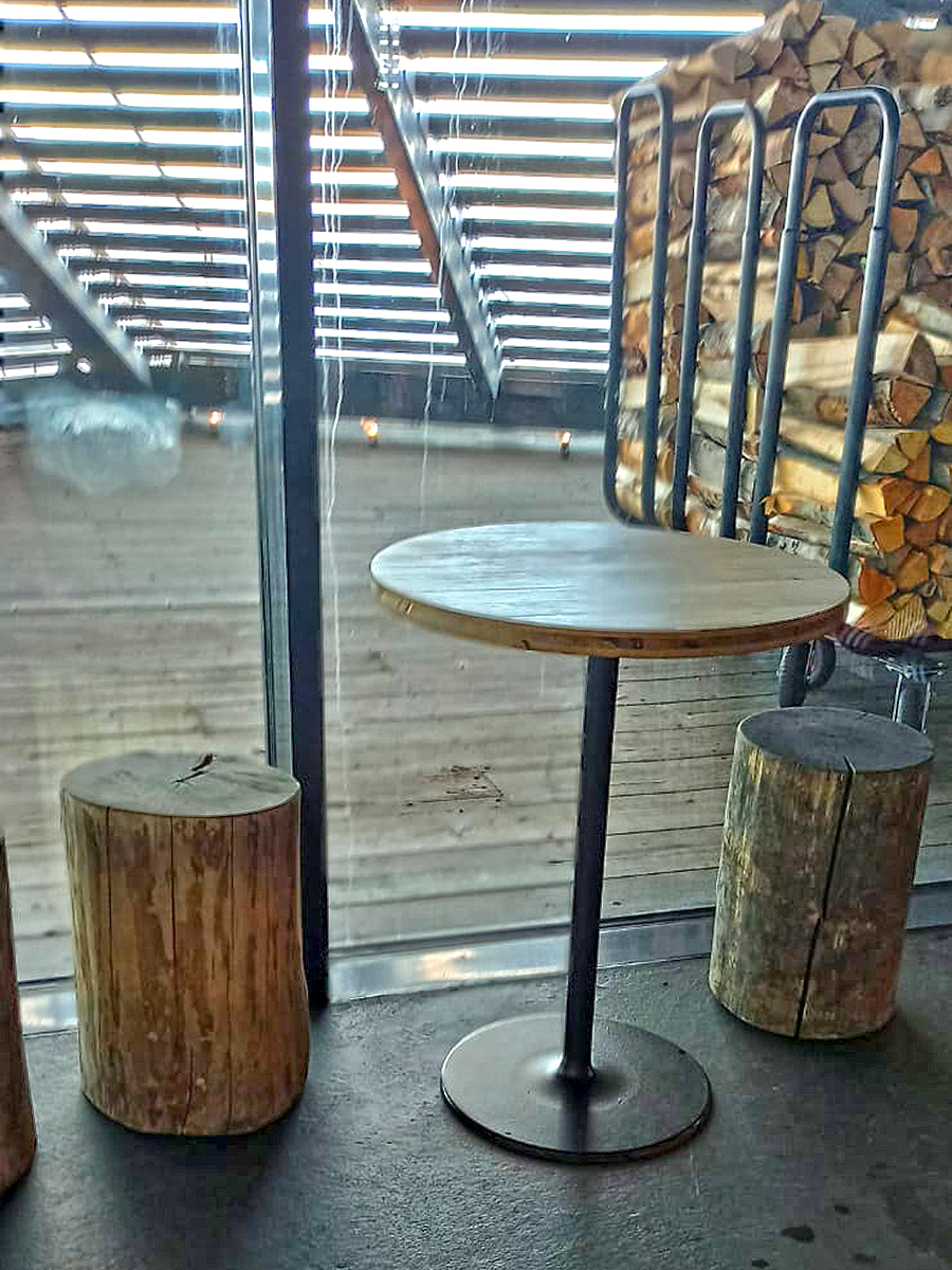 Tische und Hocker im Ruhebereich der Löylysauna. Draußen liegen die Holzscheiten, mit denen die Saunaöfen beheizt werden. (Foto: Sandra Lutz)
